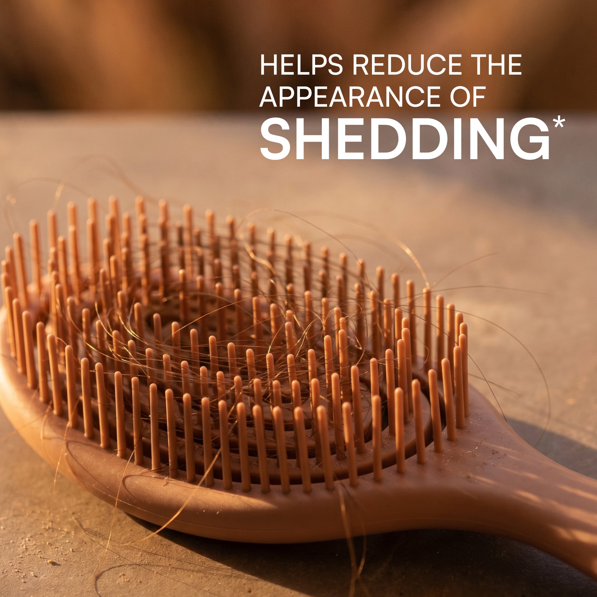 Wooden hairbrush with hair strands on a wooden surface, text 'HELPS REDUCE THE APPEARANCE OF SHEDDING'.